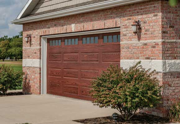 This is an image of a faux cherry wood steel garage door in a traditional style.