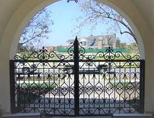This is an image of a residential automatic driveway gate composed of ornamental iron.