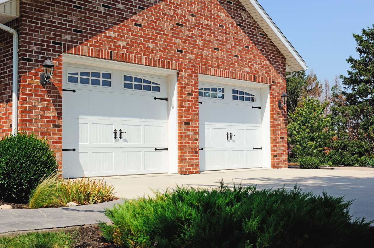 This is an image of white steel garage doors on a brick home.