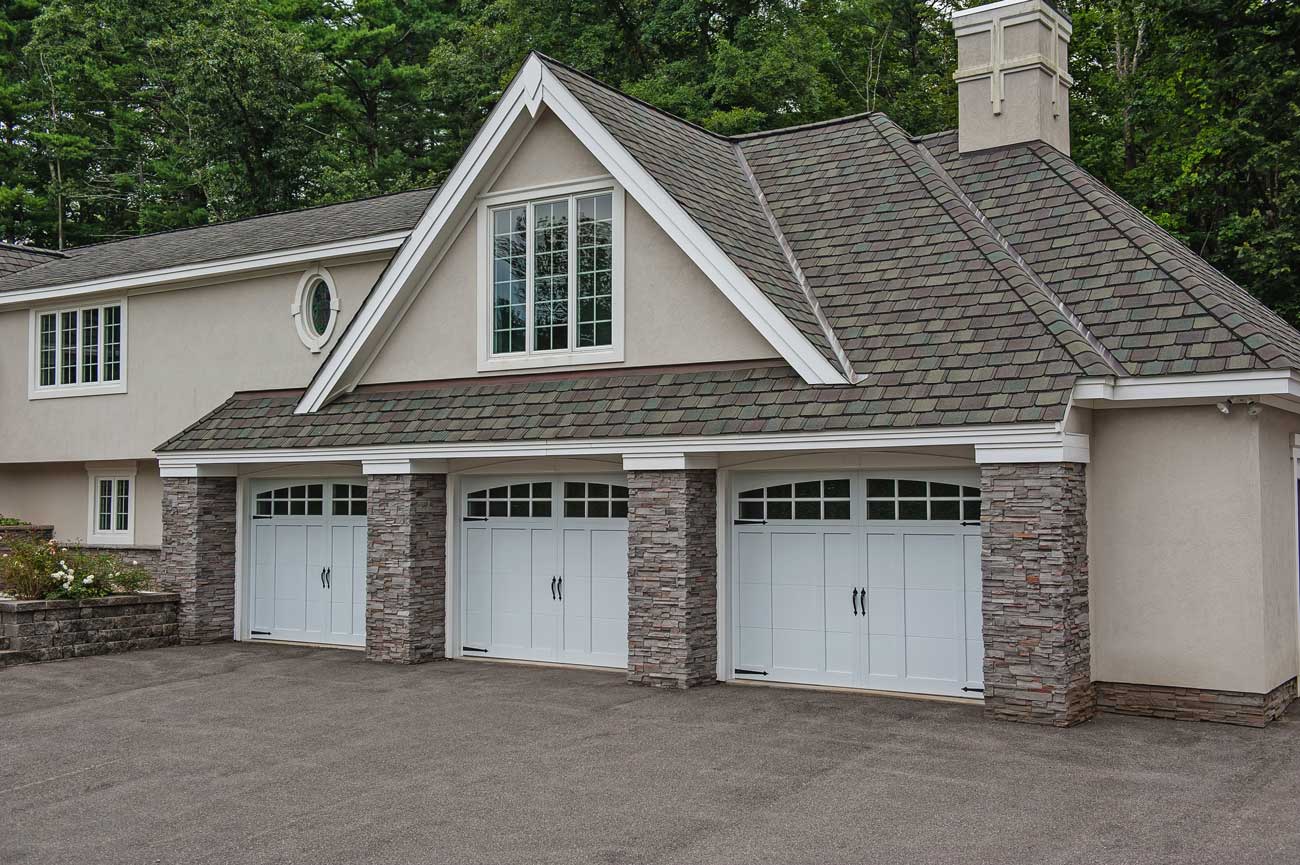 This is an image of white garage doors on a tan home with a three car garage.