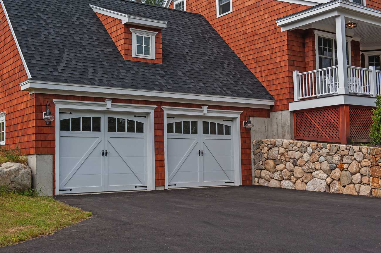 This is an image of a white carriage barn style garage door with decorative hardware and windows.