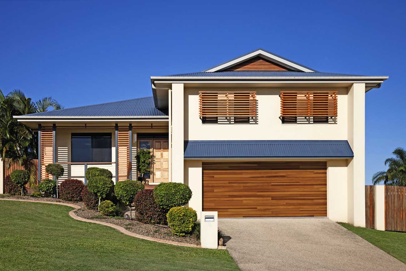 This is an image of a light faux wood steel garage door with horizontal lines on a home, no windows.