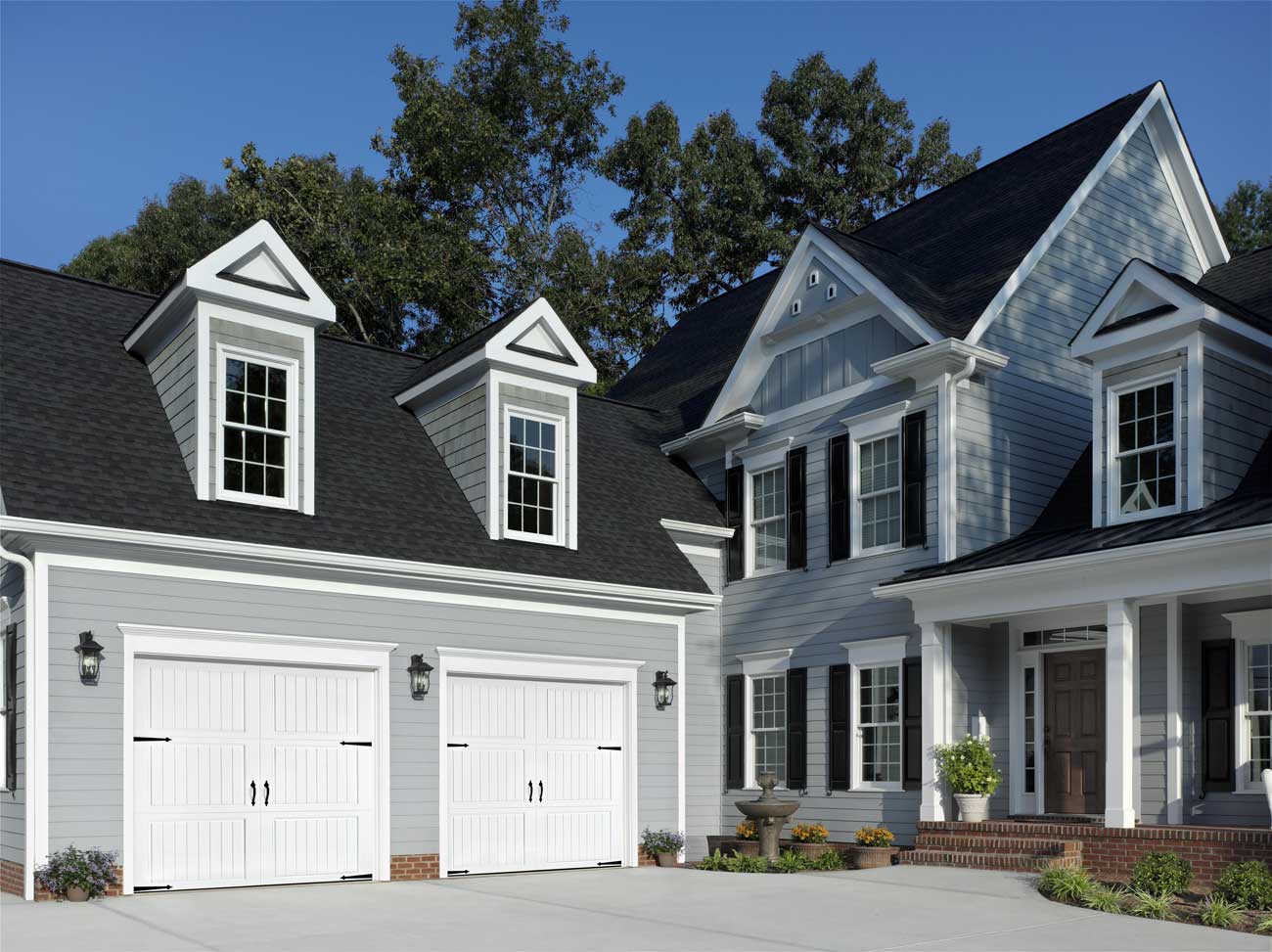 This is an image of white steel garage doors on a Cape Code home with no windows.