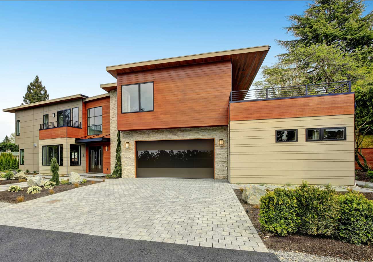 This is an image of a modern flush brown garage door with glass in the center installed on a contemporary home.